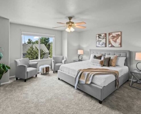 IMG_2377 Staged bedroom with a gray upholstered bed, two accent chairs, matching bedside lamps and framed artwork.
