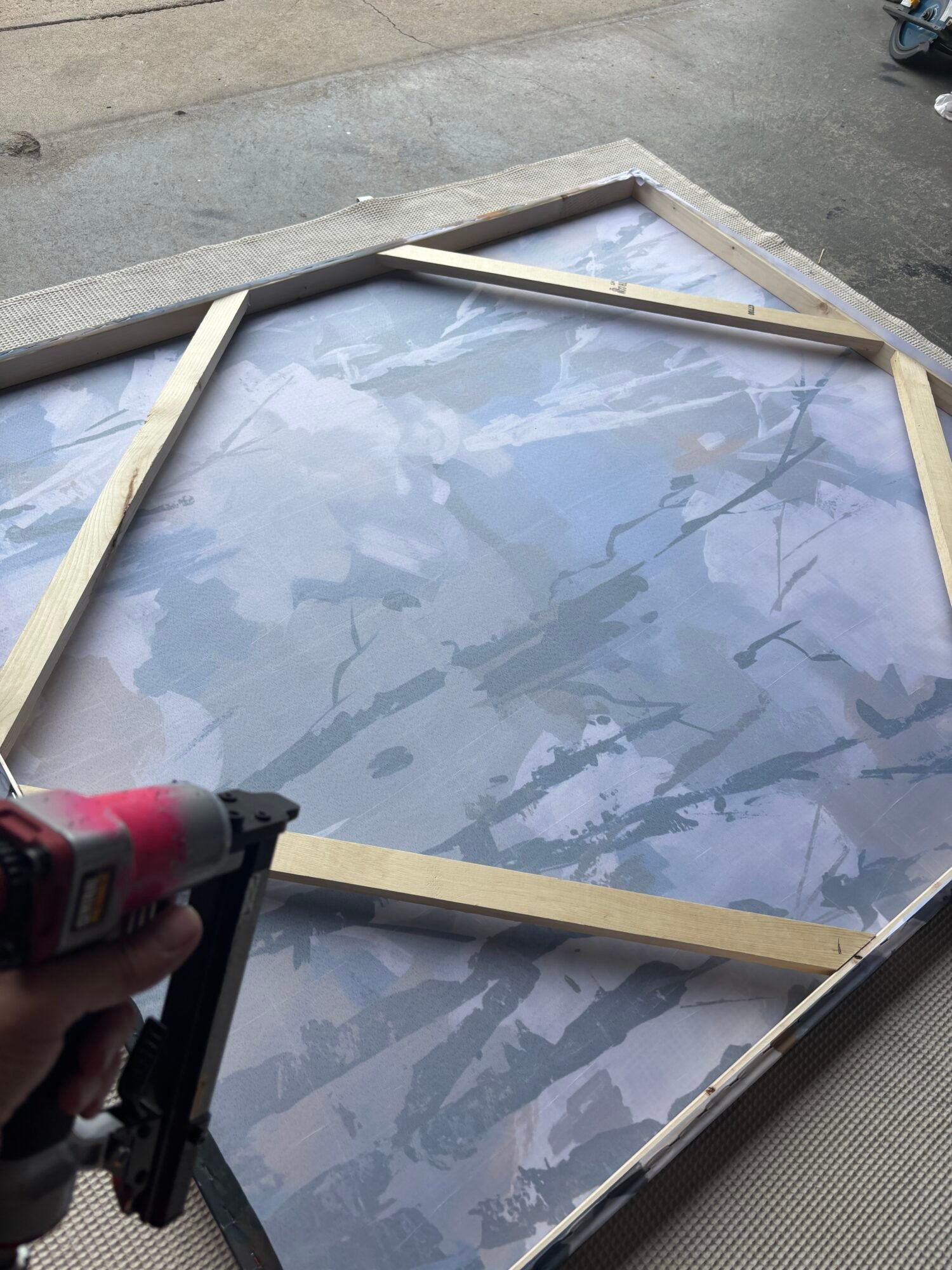 Back of a large canvas with wood frame braces and a nail gun in the workshop