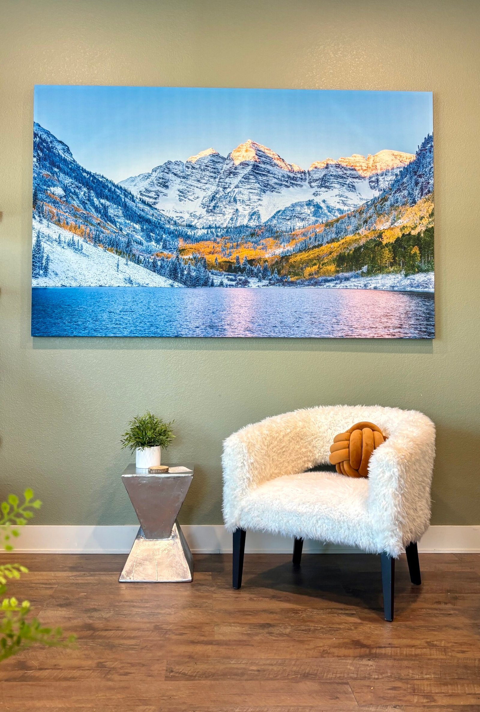 Mountain and lake canvas above a white chair in a furnished room