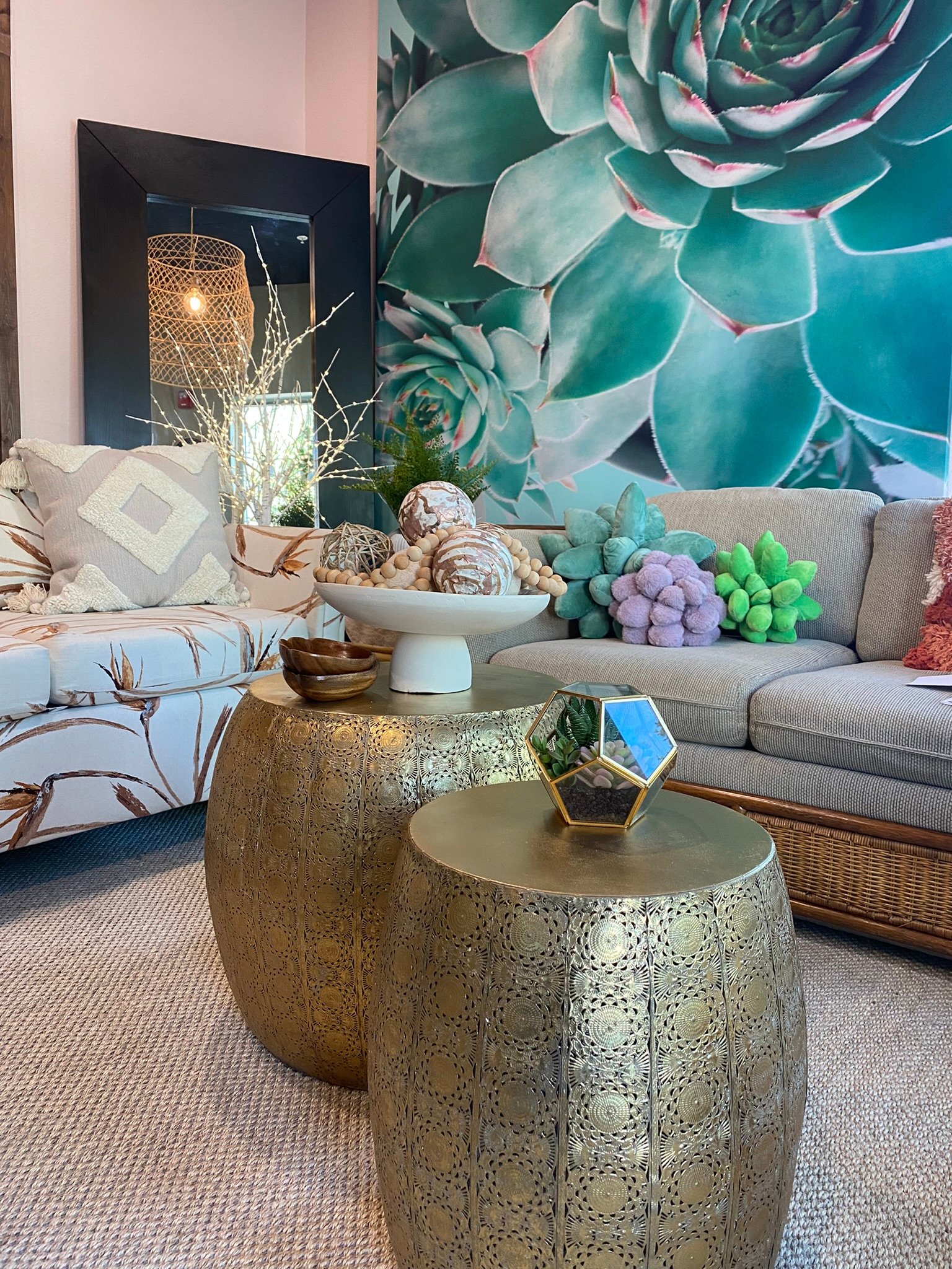 Oversized succulent wall artwork behind a styled sofa and gold coffee tables